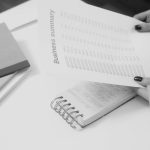 Black and white image of a businesswoman reviewing a business summary on paper.